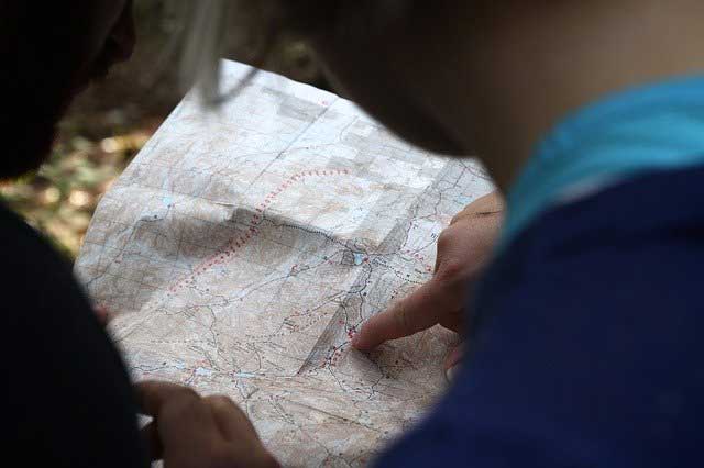 A woman pointing to a location on a map. 