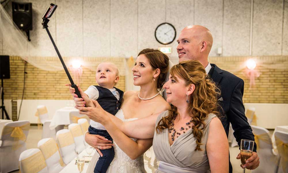 Family use a selfie stick to take a photo.