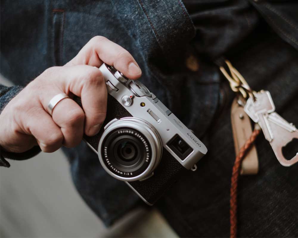 Person with finger over the shutter of the Fujifilm X100V.